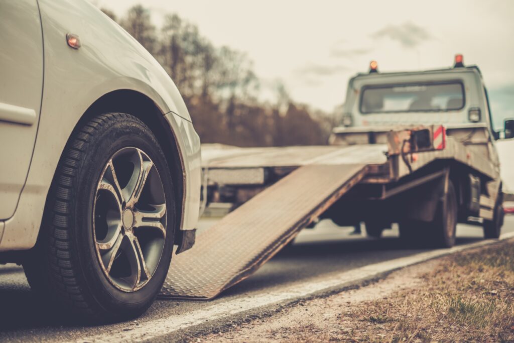 Should I Accept The First Settlement Offer? - Loading broken car on a tow truck on a roadside