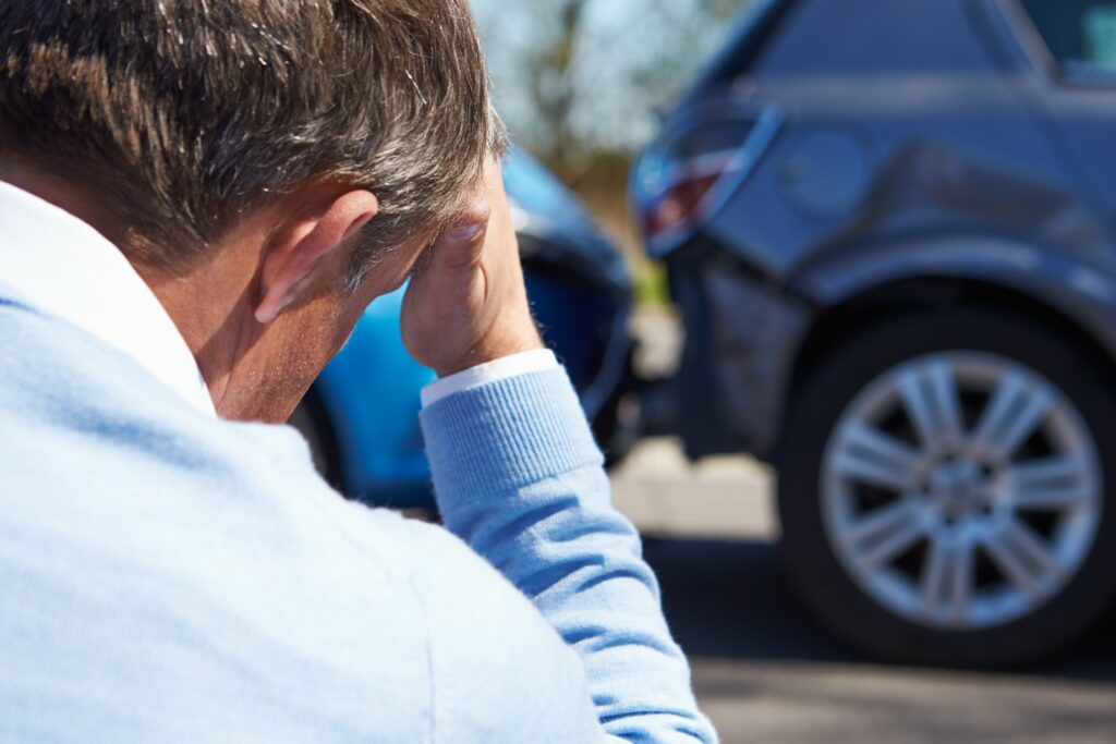 Man holding his head next to fender bender